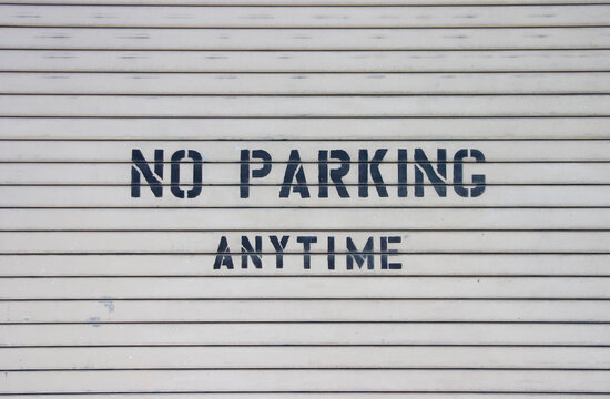 A roll-up garge has "No Parking Anytime" painted on it.