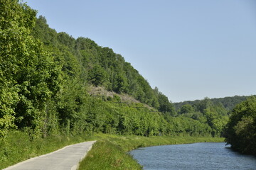 Chemin de halage le long de la Sambre dans la vallée encaissé entre les collines boisées à Thuin 