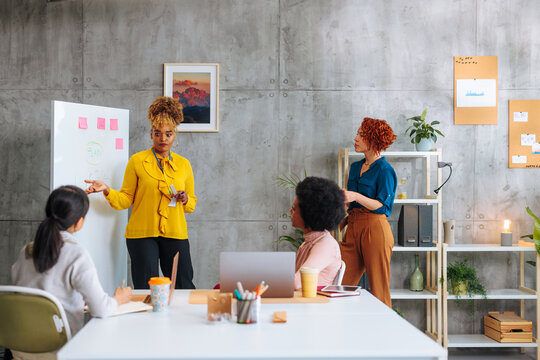 African-American business woman presenting information on board during meeting in startup office.