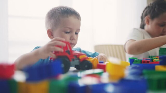 kids play in kindergarten in the constructor cubes. a group of kids play toys, blocks and cars on table in kindergarten. happy family preschool education indoors concept. baby toddler home