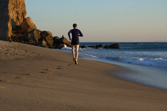 Man running on Pointe Dume beach in Malibu, CA