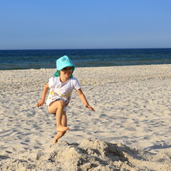 Little child playing on the sand beach during vacation at the Baltic coast