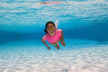 Child in swimming pool on ring toy. Kids swim.