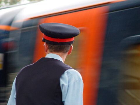 A station master overlooking departing train at Durham station, UK