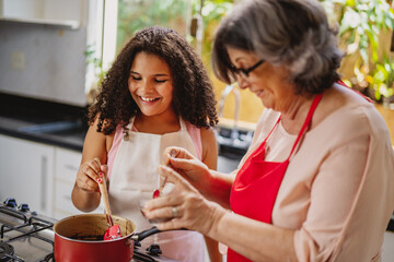 Avó e neta Brasilieiras se divertindo na cozinha enquanto preparam um receita para o dia das mães