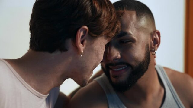 jovem casal gay inter racial brasileiro sentado na cama se olhando intensamente