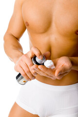 Muscular man's taking shave foam on his hand. Isolated on white in studio.