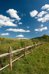 Fototapeta na wymiar East European summer landcape with wooden fence and beautiful clouds