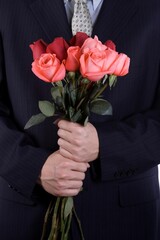 A man with business suite holding roses proposing.