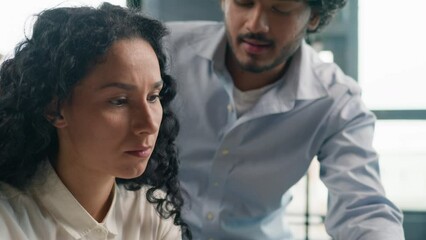 Leader mentor Indian Arabian man boss teach intern help woman with laptop program check documents in office multiracial businessman and businesswoman solve difficulties together business discussion 