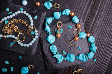 author collection jewelry with azure gemstones, pearls and chain demonstrated at black stones background.  fashion and jewelry concept. flat lay. close up