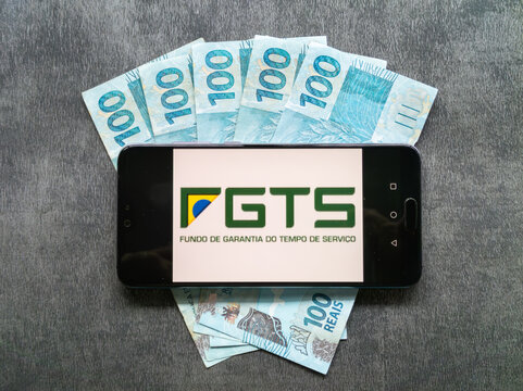 Bahia, Brazil, 02 june 2023. FGTS (Brazilian Guarantee Fund) application on the smarthphone screen about banknotes of one hundred Brazilian reais