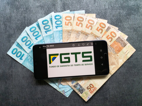 Bahia, Brazil, 02 June 2023. FGTS (Brazilian Guarantee Fund) application on the smarthphone screen on Brazilian money notes