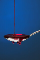 Spoon full of cough medicine over a blue backdrop 3