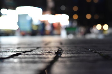 Brick Sidewalk at Night in New York City, Blurred Nightlife in Distance 