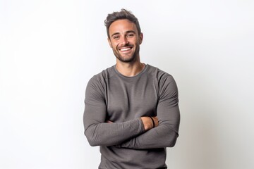 Portrait of handsome young man smiling with arms crossed against white background