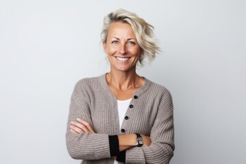 Portrait of smiling middle aged woman with arms crossed against white background