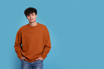 Portrait of handsome young man on light blue background. Space for text