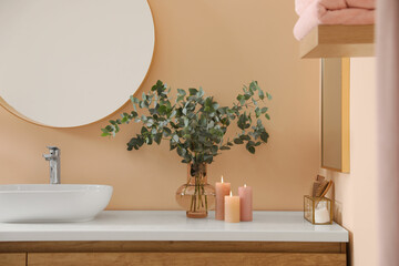 Stylish mirror, eucalyptus branches and vessel sink in modern bathroom. Interior design