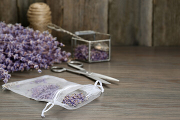 Obraz na płótnie Canvas Scented sachet with dried lavender flowers on wooden table, space for text