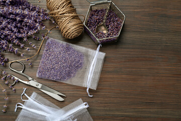 Scented sachet with dried lavender flowers, scissors and twine on wooden table, flat lay. Space for...
