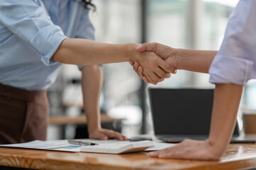 Two businesswoman shaking hands for success. Handshake. Collaboration, teamwork, friendship. Meeting of financial business partners, paperwork, calculations, investments, company partnerships.