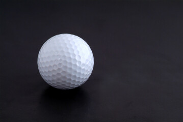 Golf ball and yellow, wooden tee on black background
