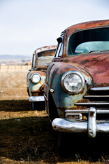 vintage car - two vintage cars abandoned on a field in rural wyoming. vertical version.