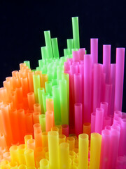 abstract ’skyline’ of colourful plastic drinking straws against black ground