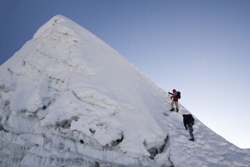 Two climbers about to summit Island Peak in Nepal. The peak is very close to Everest and Lhotse. This picture was taken in in the middle of October at 6:45am.