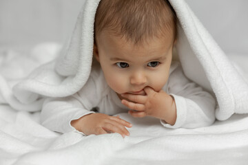 Little infant baby lying on white soft blanket at natural light, candid portrait of newborn child