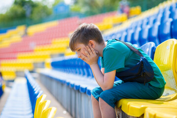 a sad, tired boy sits on a sports podium alone