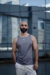 A man pauses during an outdoor workout to pose for a portrait. His gray tank top shows off his...