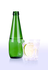 glass of mineral water with lime and green bottle with path