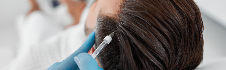 Cosmetologist in gloves does vitamin injection in patient head skin during meso therapy