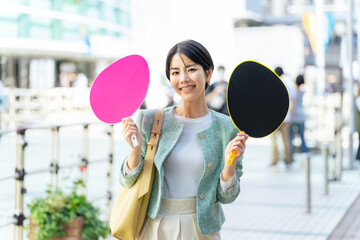 応援うちわを持ってコンサート会場の前に立つ女性　推し活