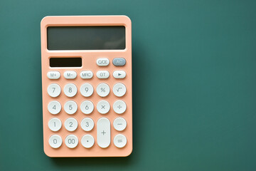 modern peach colour pastel calculator and white button on green background, business and finance accounting concept