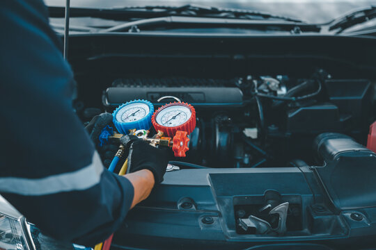Close up hand of auto mechanic using measuring manifold gauge check the refrigerant and filling car air conditioner for fix and checking for repair service support maintenance and car insurance.