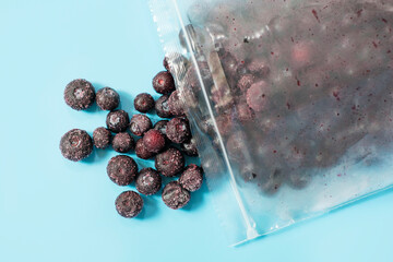 Packages with frozen blueberry on blue background, top view.