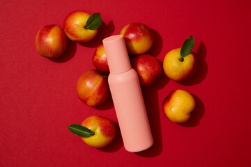 Deep red background with several peaches displayed with a bottle. Peach (Prunus persica) will help maintain a healthy weight. Branding mockup with empty label