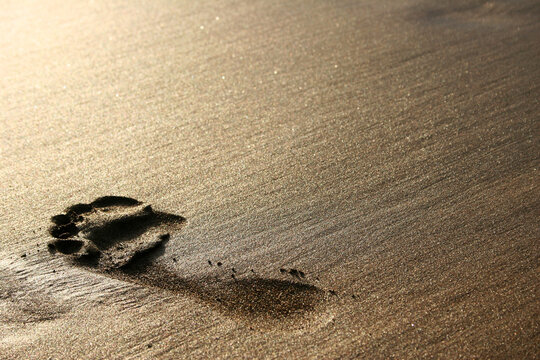 Big footprint on golden sand at sunset