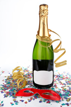 Champagne bottle with red mask, ribbons and confetti. Blank label for add text