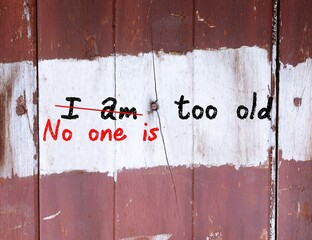 Grunge old wood wall with handwritten chalk text I AM TOO OLD, changed to NO ONE IS TOO OLD, to...
