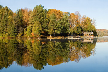 Boat docks and fall trees, along the shore of a clear blue lake.