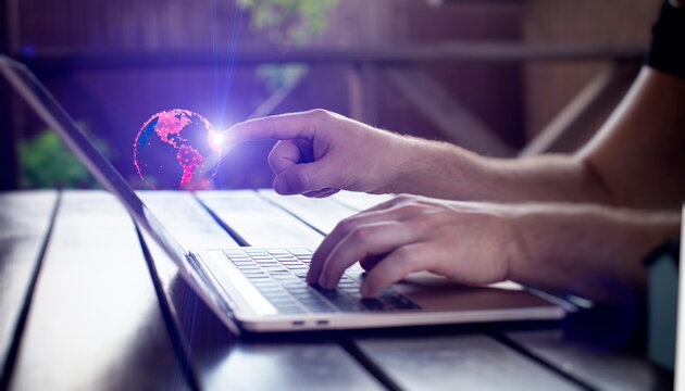 Man using laptop with digital sphere hologram on blurry background. Technology concept