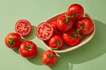 A basket full filled with red tomatoes and tomato cut in half. Tomato (Solanum lycopersicum) is a source of nutrients such as potassium, vitamin A, vitamin B, magnesium