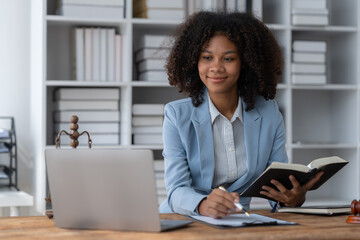 American woman lawyer or businesswoman African working with laptop, searching, analyzing data, reading contract documents work with law books hammer of justice Consulting lawyer concept.