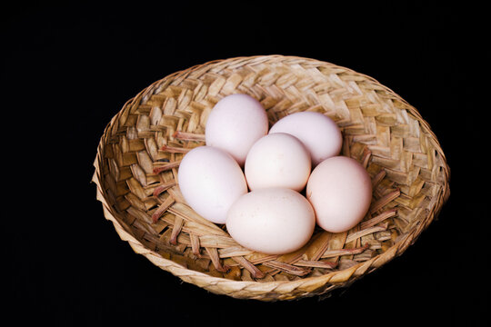 White free-range chicken eggs placed on a woven plate