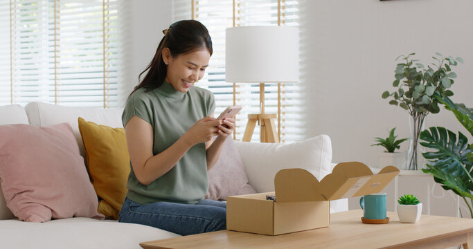 Young asia people happy girl smile unbox open gift buy order from online store shop take photo shoot camera post social media IG reel app show youth lifestyle blog share sit relax at home sofa couch.