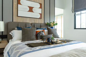 Interior of modern spacious master bedroom with big bed under a wall decoration and brown carpet.